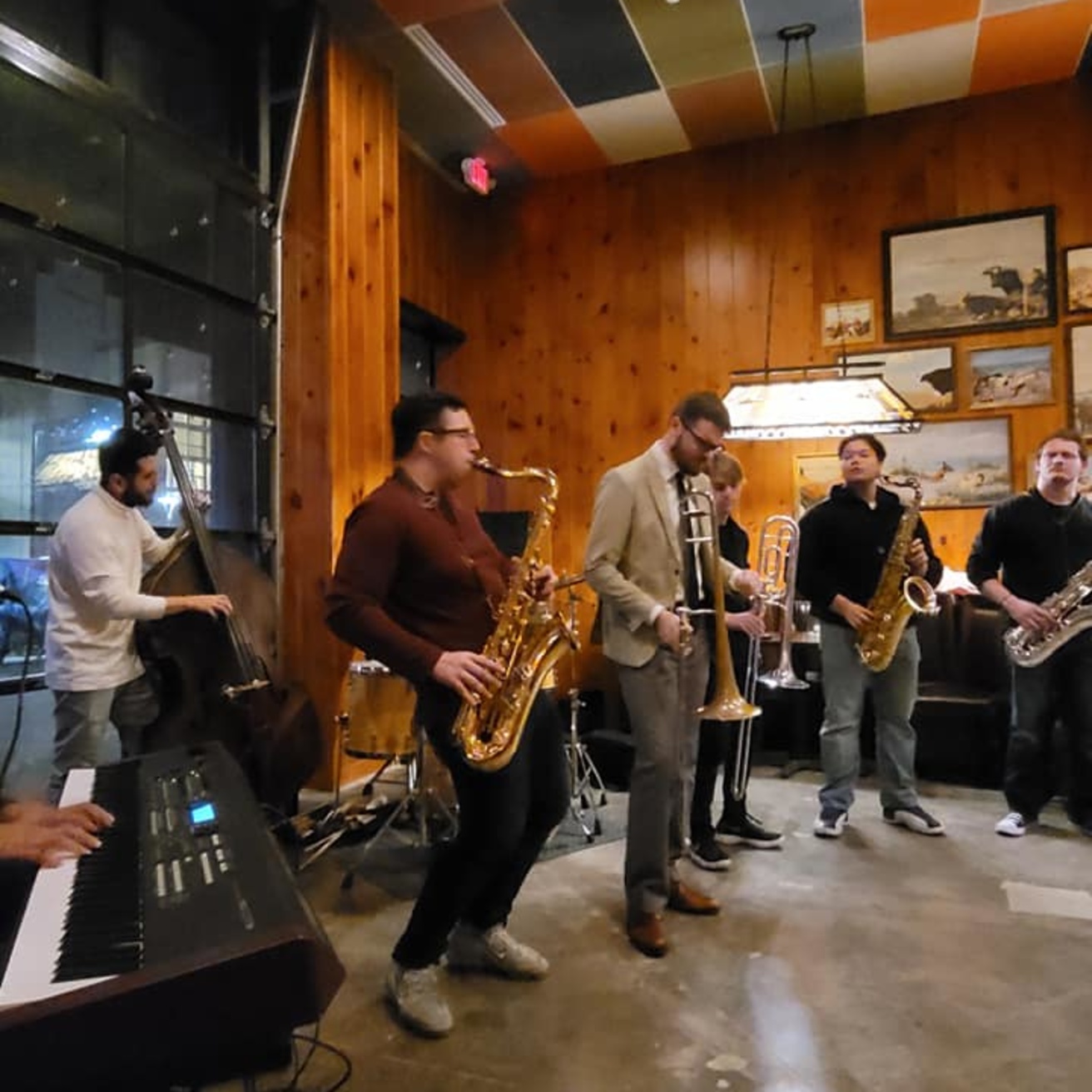 a recent jazz jam session with students  shown playing bass, saxophone, trumpet, trombone in a retro-styled restaurant setting