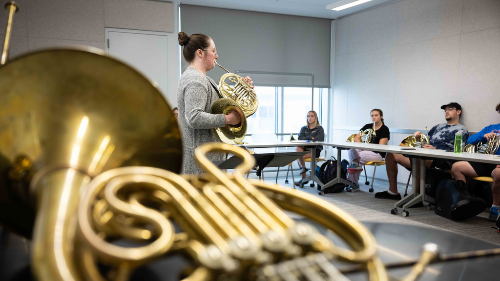 french horn in foreground and student playing in the back ground