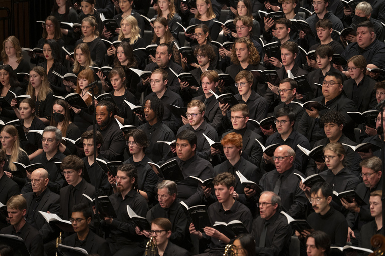 a large choir with many diverse singers dressed in black