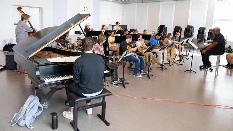 pianist in foreground with jazz ensemble rehearsal