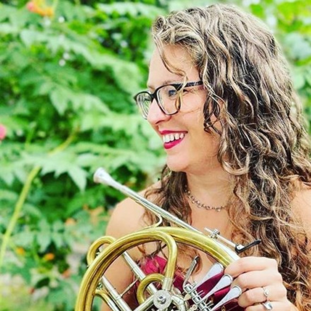 katelyn halbert holding her french horn in front of a green background