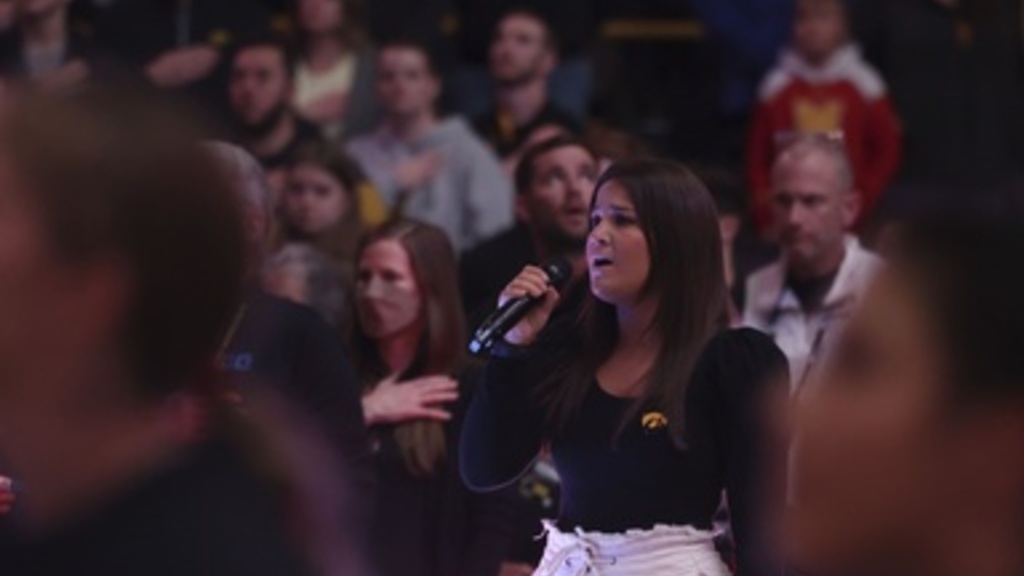 Student Alix Bushard singing the National Anthem at an Iowa Women's Wrestling match in 2024