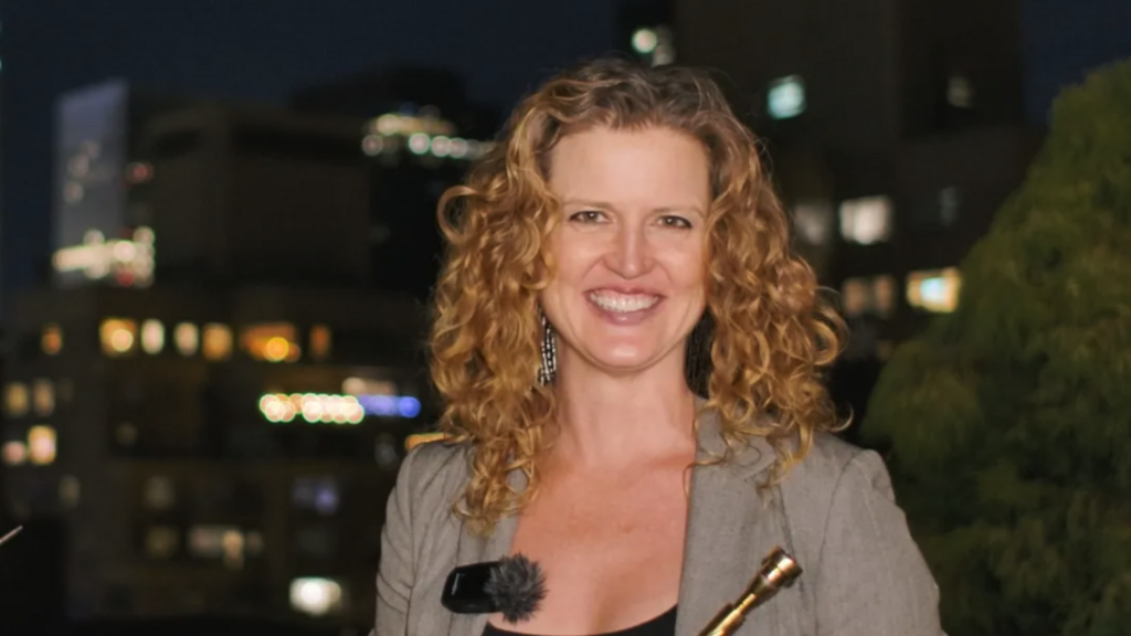 Alicia Rau smiling and holding a trumpet against a nighttime NYC skyline