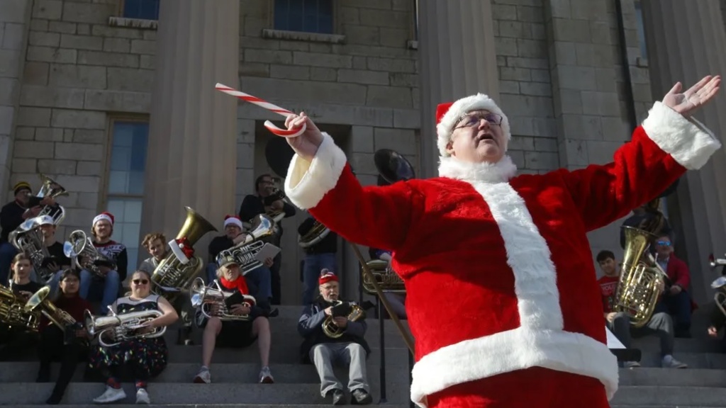 Tuba professor John Manning, conducting the low brass group on the steps of the Old Capitol wearing a Santa suit