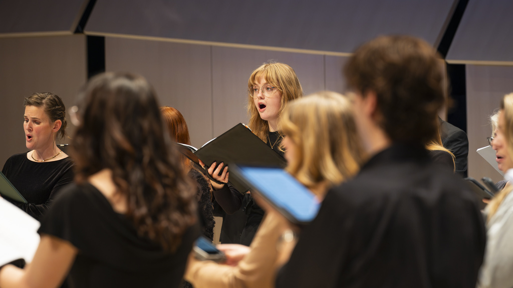 singers in a choir onstage in Voxman Music Building Concert Hall