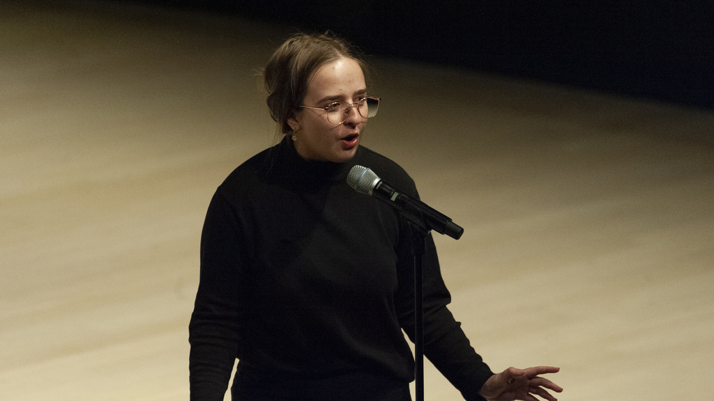 a student vocalist singing into a microphone onstage in the concert hall