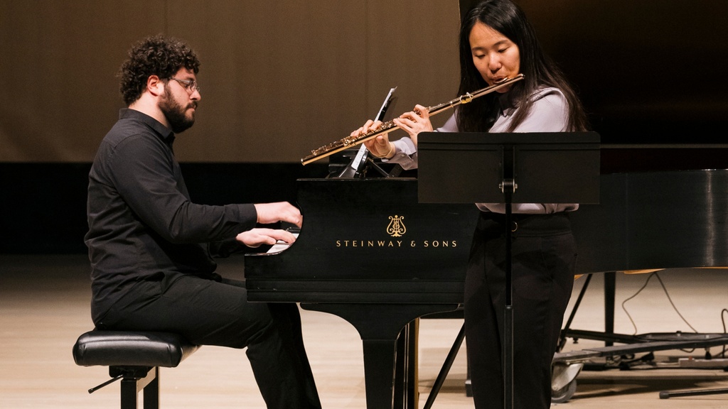 flutist and pianist performing together in concert hall