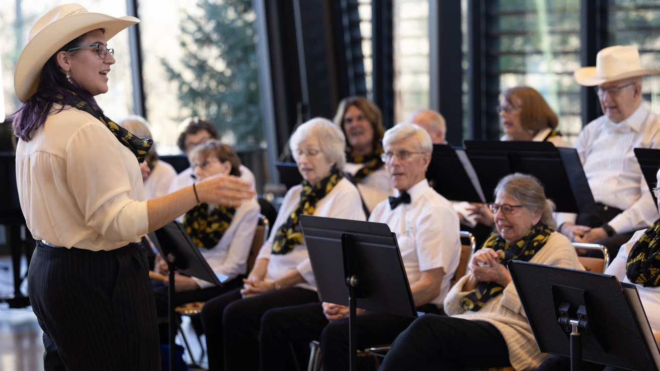 woman in cowboy hat directing a choir of older adults